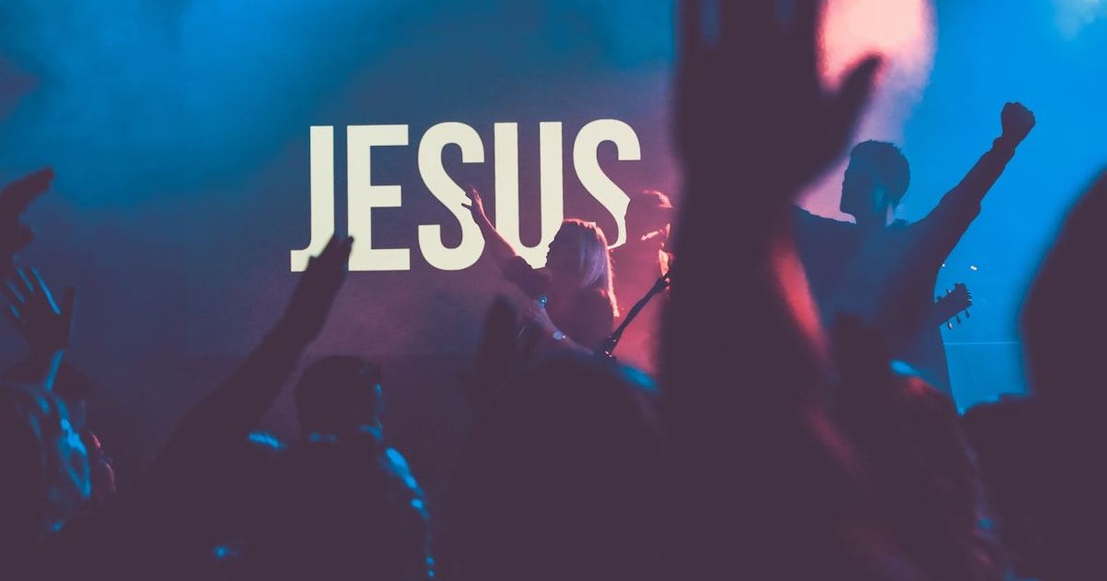 A congregation with raised hands at a large worship gathering