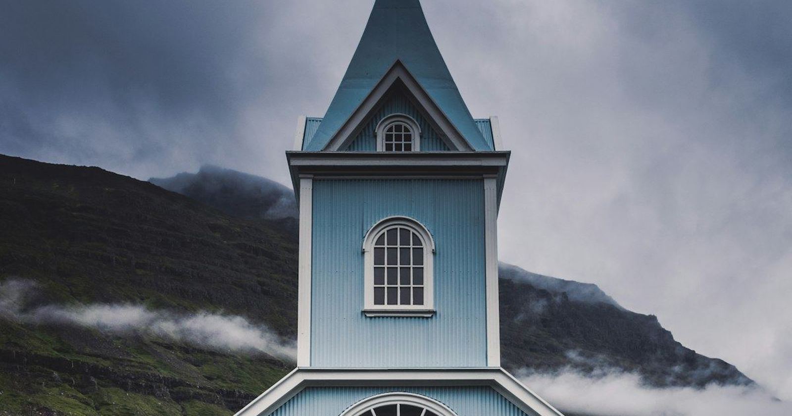 A small white country church standing against green hills