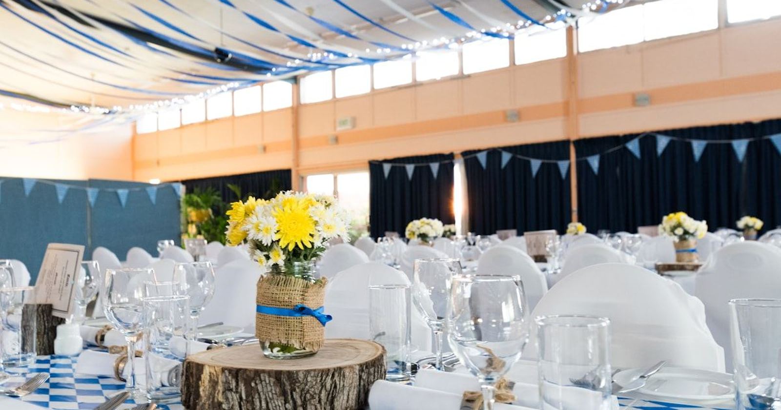 A long celebration table laid with blue and white linen and simple flowers