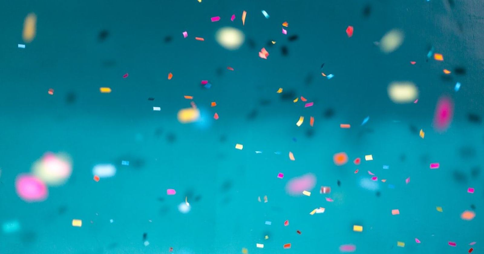 Bright confetti suspended in the air against a clear teal background