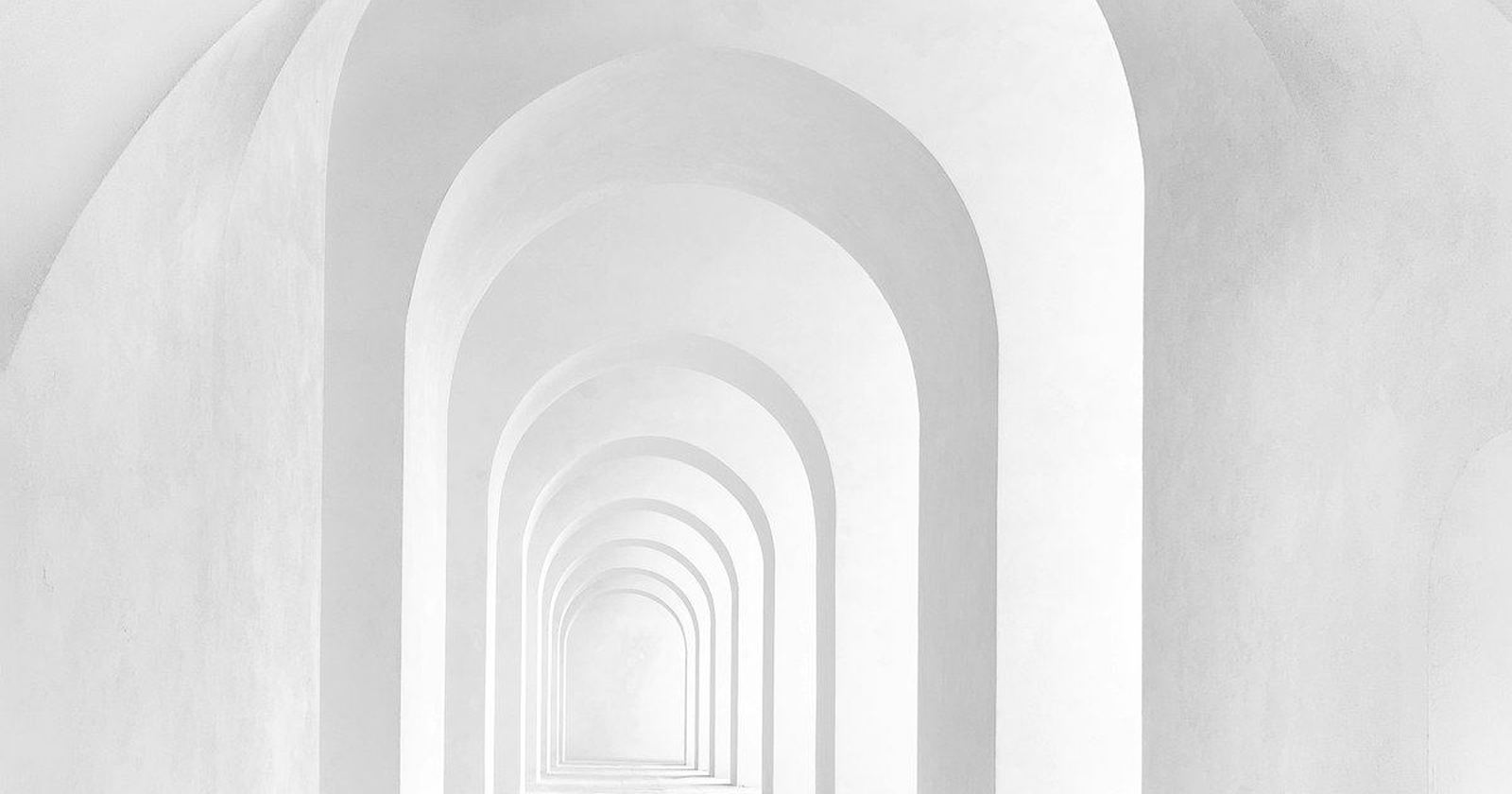 A quiet white archway corridor receding into soft light