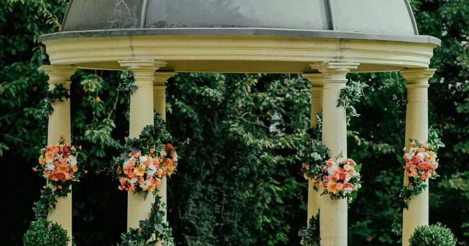 A floral ceremony arch framing a garden setting