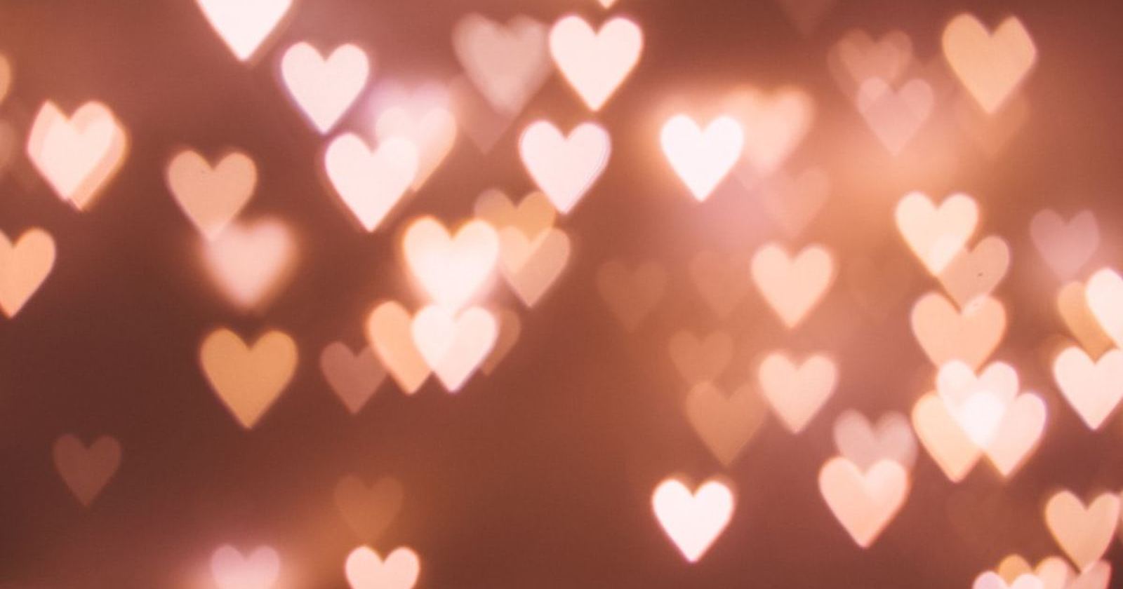 Warm heart-shaped points of light blurred across a dark background