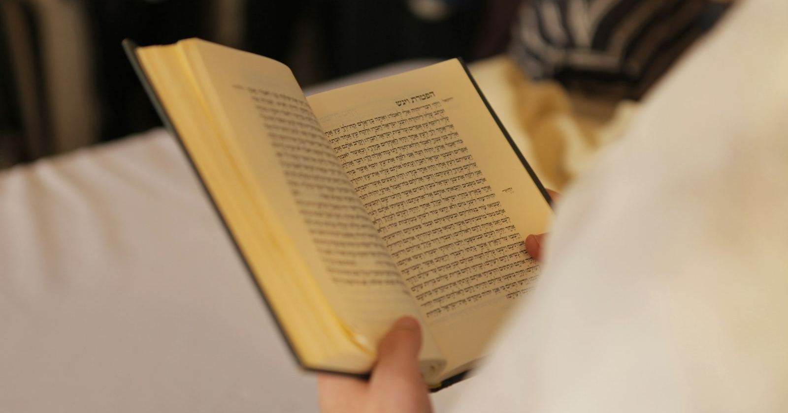 A bar mitzvah boy reading the haftarah from a book during the synagogue service