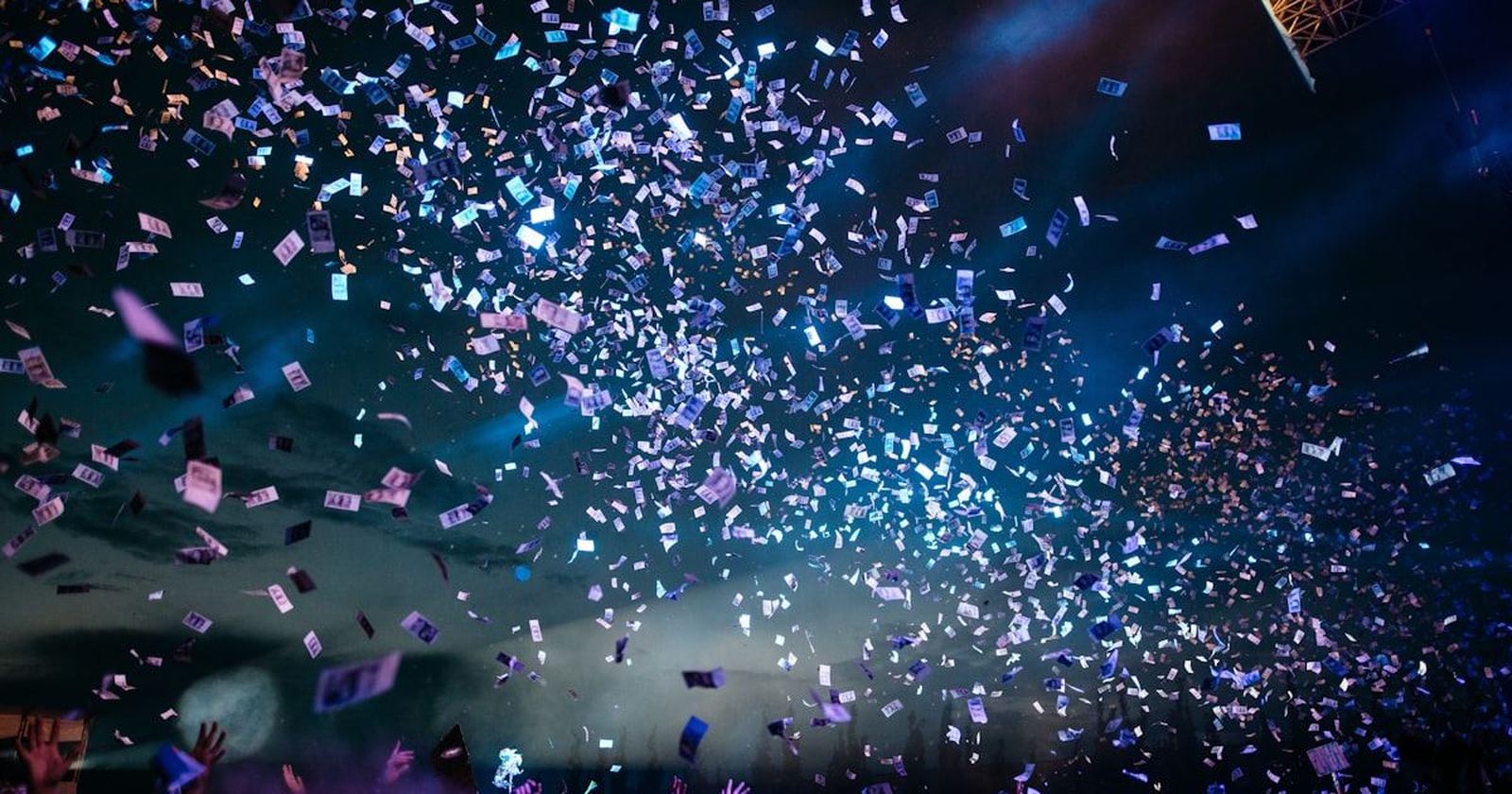Confetti bursting over a crowd in a darkened room