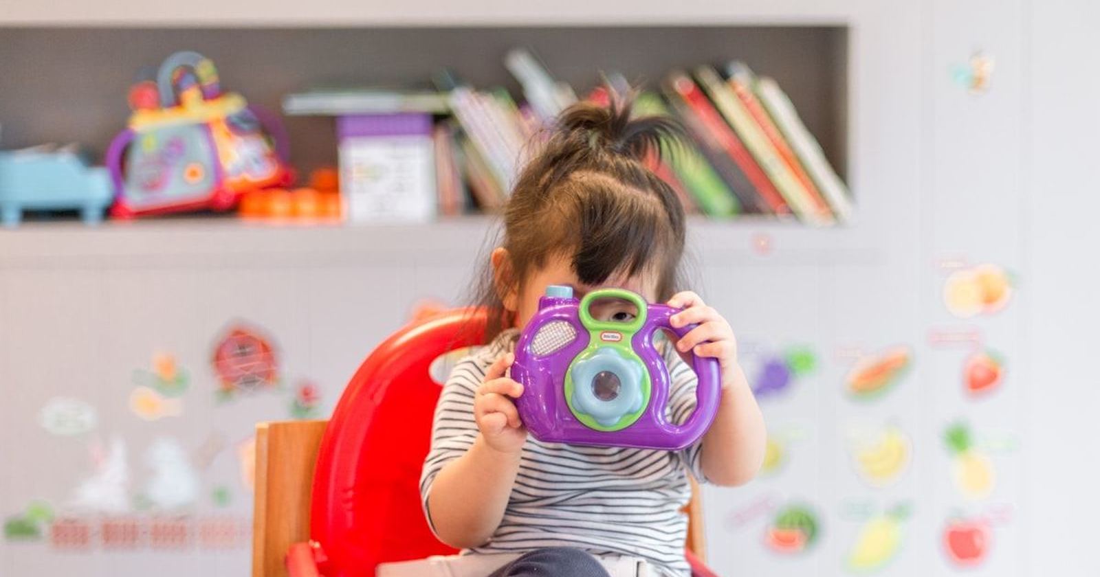 A small child holding a toy camera up to their face