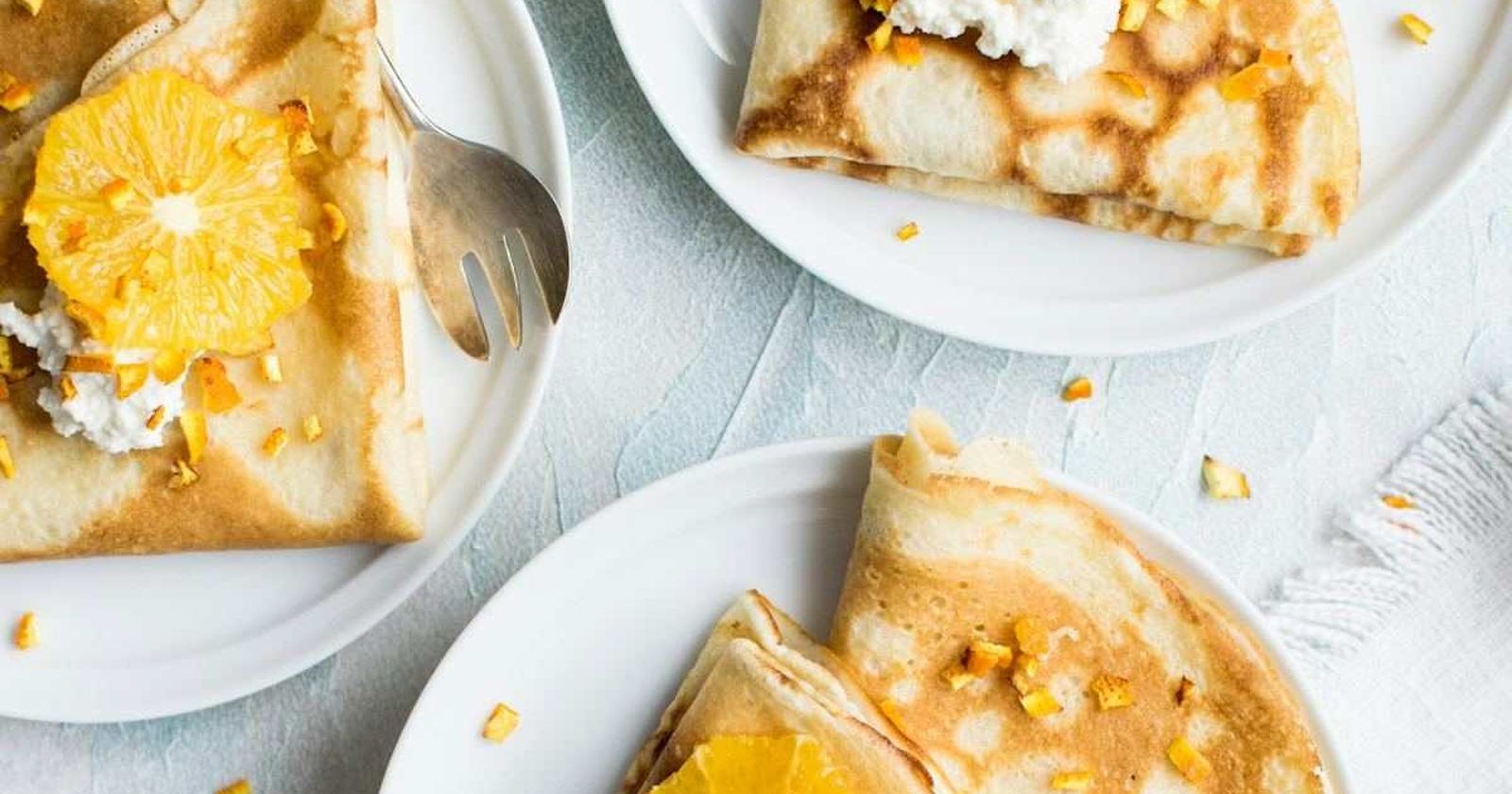 A brunch table photographed from above with crepes, fruit and coffee