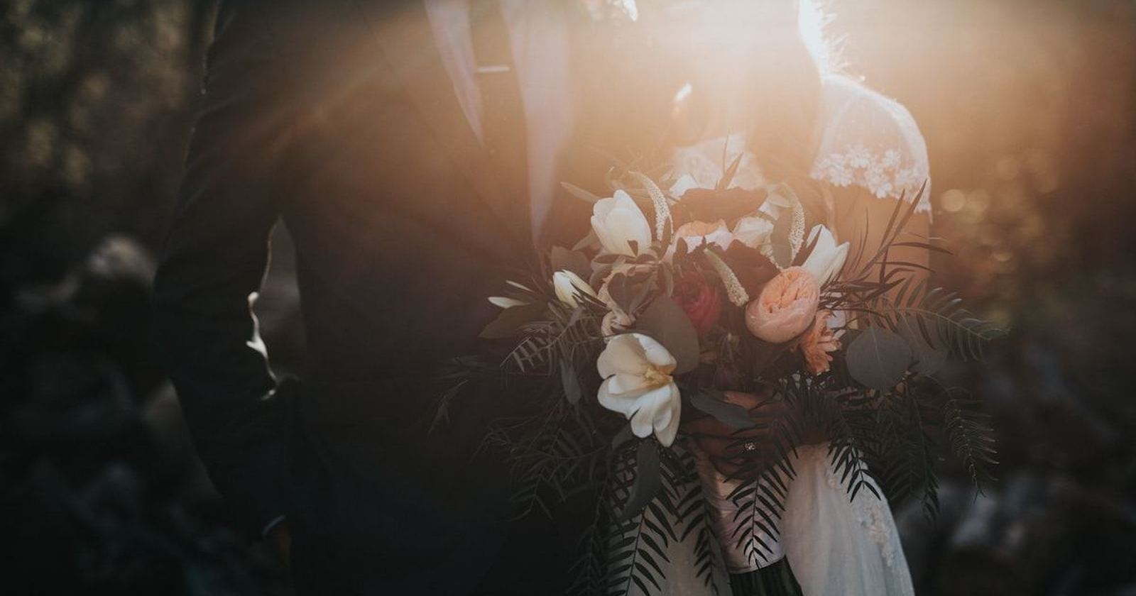 A couple silhouetted at dusk, the bride holding her bouquet at her side