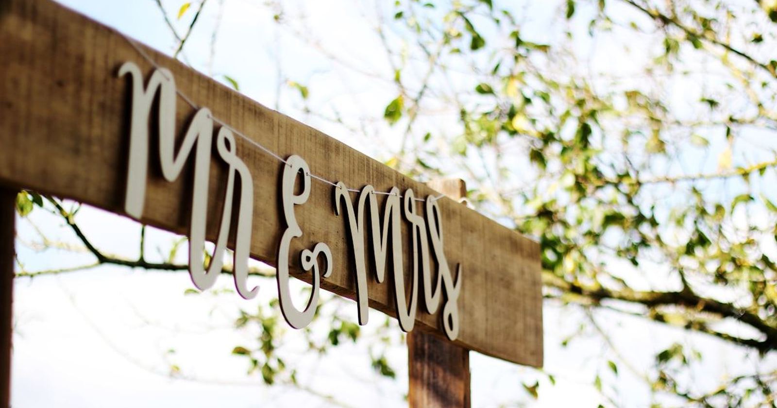 A hand-painted wooden Mr and Mrs sign hanging in dappled sunlight