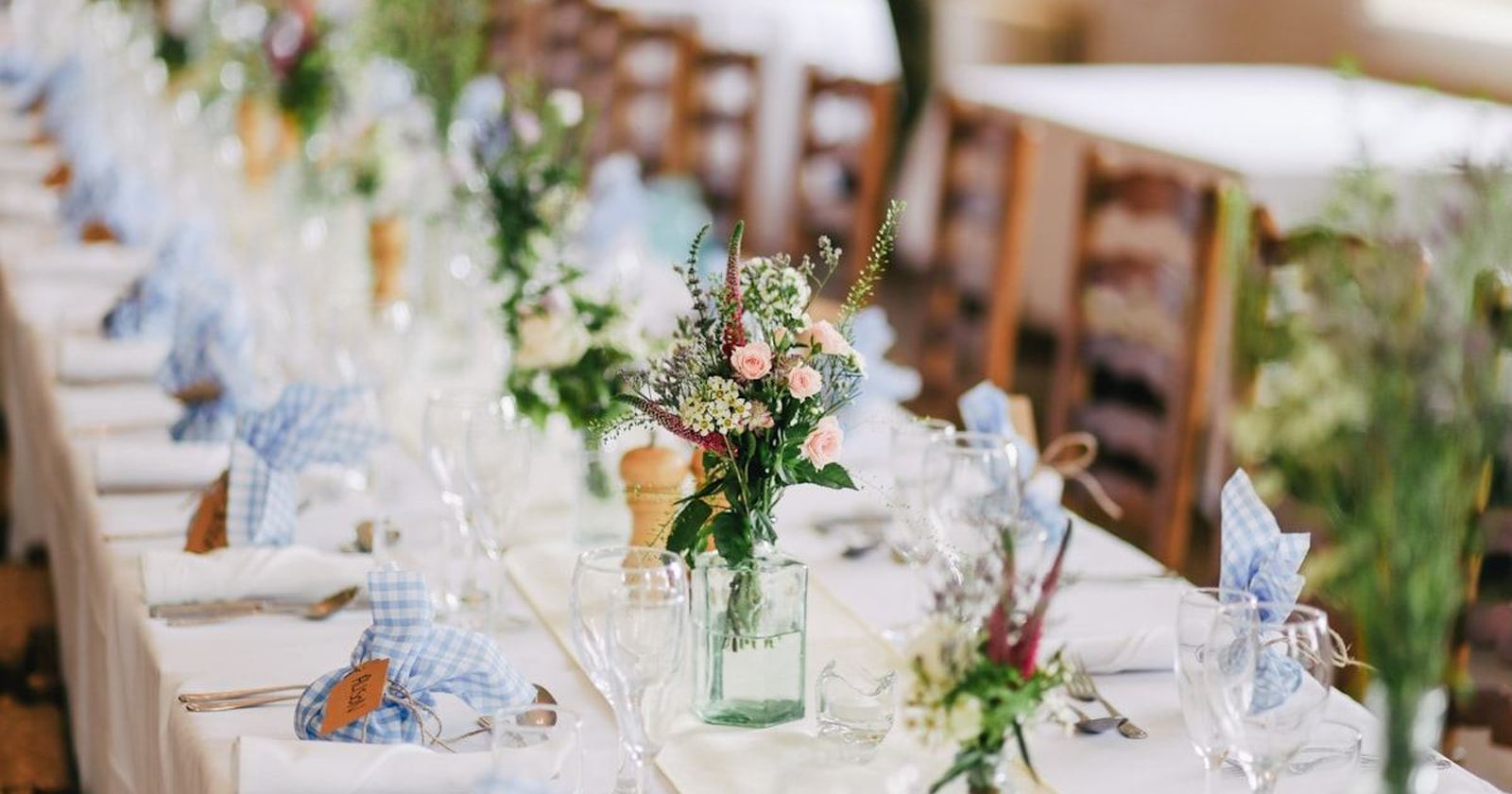 A long reception table dressed with white linen and low floral arrangements